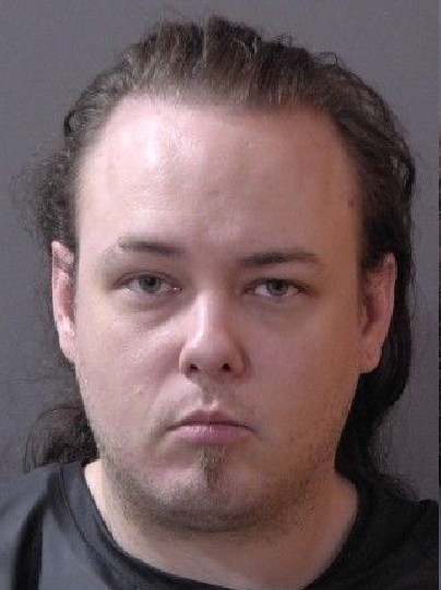 Headshot of a man with a serious expression, wearing a dark shirt.