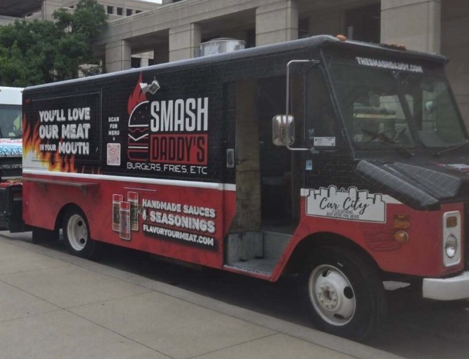 A food truck with the branding "SMASH DADDY'S BURGERS FRIES ETC" and "HANDMADE SAUCES & SEASONINGS" parked on a city street.