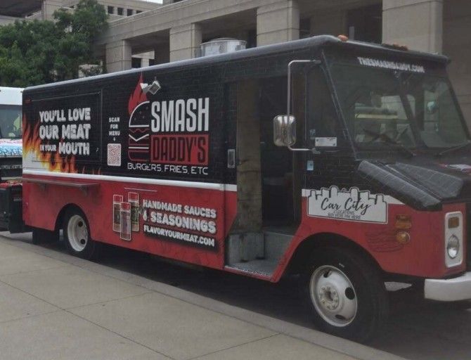 A food truck with the branding "SMASH DADDY'S BURGERS FRIES ETC" and "HANDMADE SAUCES & SEASONINGS" parked on a city street.