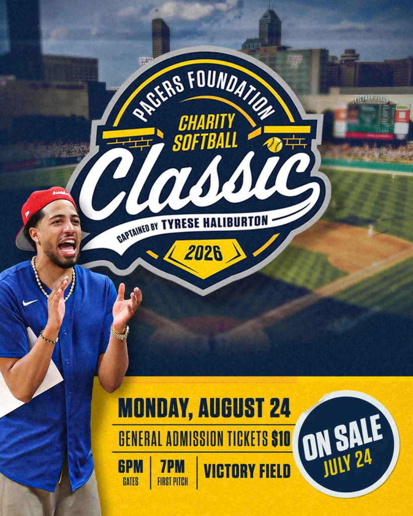 A man in a blue shirt and baseball cap applauding in front of a sign for the Pagers Foundation Charity Softball Classic event on August 24, 2026 at Victory Field.