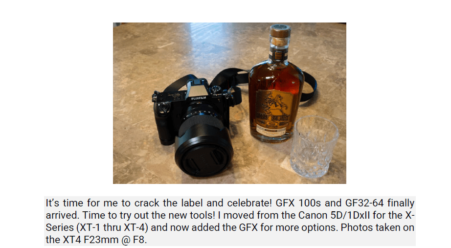 A Fujifilm camera, a bottle of Nikka whisky, and two crystal glasses on a stone surface.