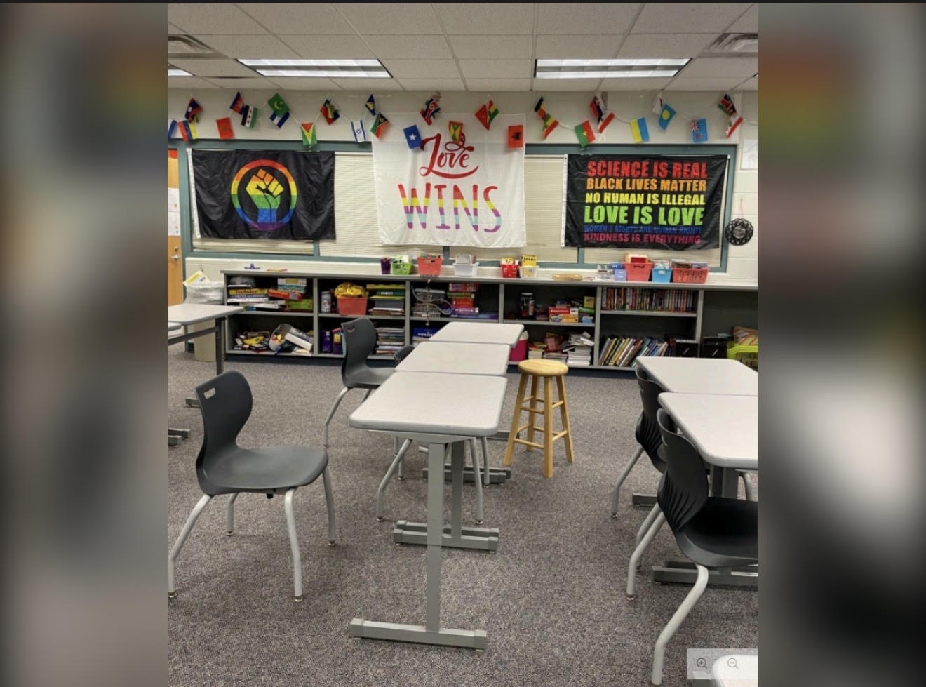 Classroom with diverse decor and signage, including "Love Wins", "Science is real, Black lives matter, no human is illegal, Love is love", and a rainbow flag.