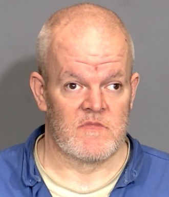Headshot of a middle-aged man with a gray beard wearing a blue shirt.