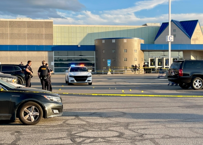 Police officers standing near a police vehicle in front of a large commercial building.