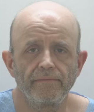 Headshot of a bald, bearded man with a serious expression.