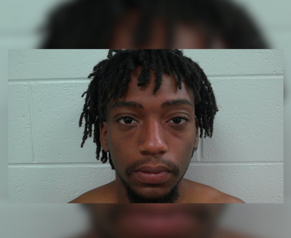 Close-up portrait of a young Black man with dreadlocks looking directly at the camera.