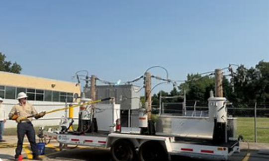 A utility truck with equipment on a trailer parked in a grassy area, with a worker standing nearby.