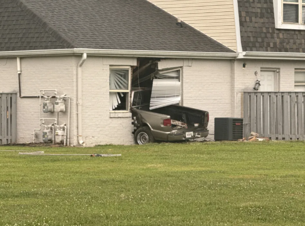 A vehicle has crashed through the wall of a residential building, causing significant damage.
