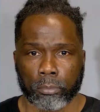 A middle-aged Black man with a beard and short curly hair, looking directly at the camera with a serious expression.