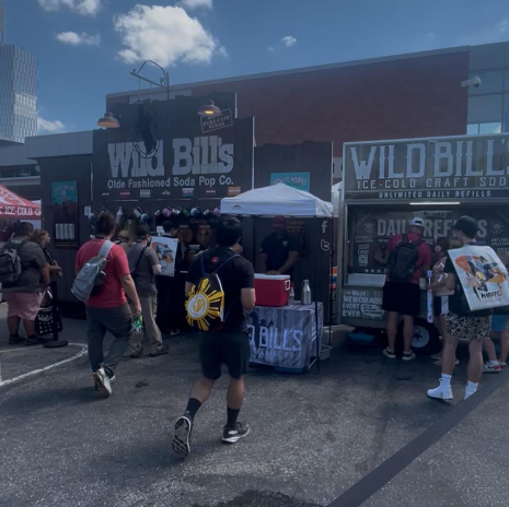 Outdoor food and drink vendor stall with "Wild Bill's" branding, surrounded by a crowd of people.