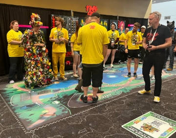 A group of people wearing yellow shirts standing in a room with colorful floor graphics.