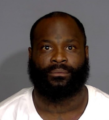 Headshot of a Black man with a full beard wearing a white shirt.