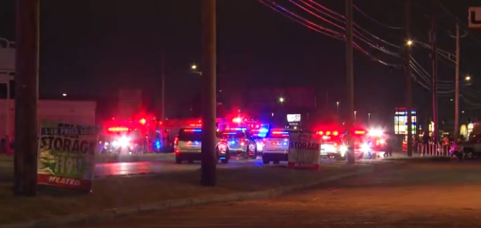 Emergency vehicles with flashing lights on a dark street at night.