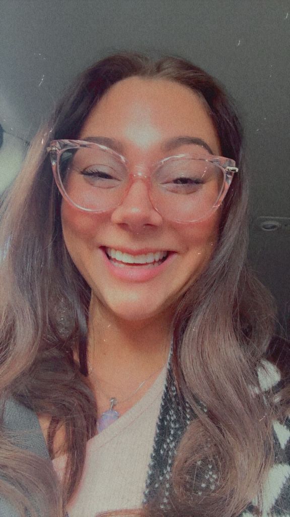 A smiling young woman wearing glasses and looking directly at the camera.
