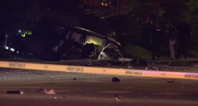 Damaged vehicle on dark street at night, with debris and police tape visible.