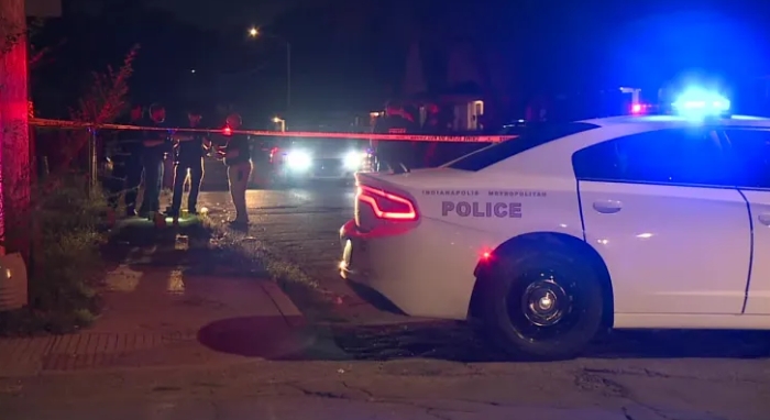Police vehicle with flashing lights at a nighttime crime scene with police officers present.