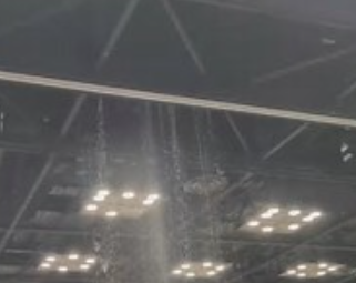 Overhead view of a large indoor space with a grid of bright lights and a water sprinkler system.