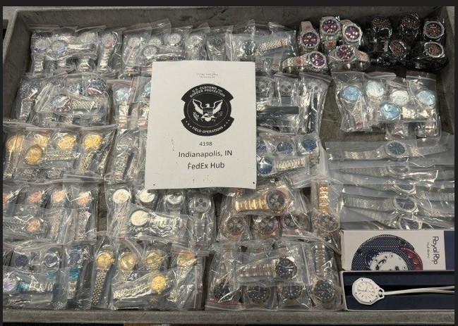 A collection of various items, including jewelry, accessories, and other small objects, displayed in clear plastic bags and containers, with a sign indicating the location as the Indianapolis FedEx Hub.