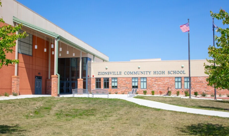 Zionsville Community High School, a brick building with an American flag flying, surrounded by trees and a grassy lawn.