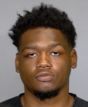 Headshot of a young Black man with short curly hair and a beard, looking directly at the camera with a serious expression.