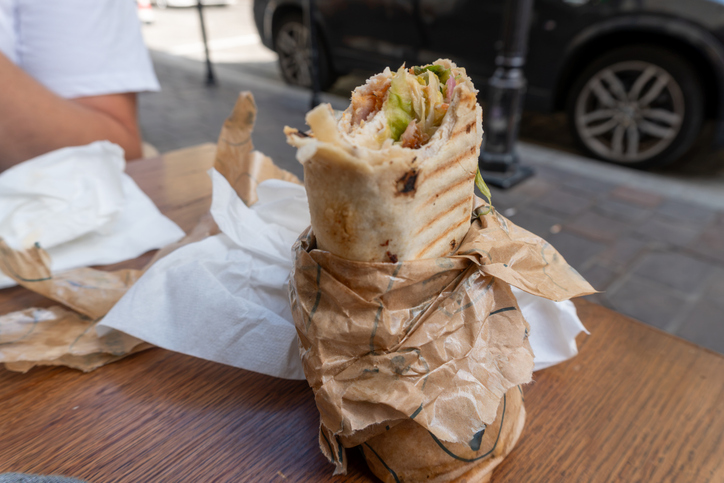 Fresh grilled chicken wrap with vegetables served on a wooden outdoor table