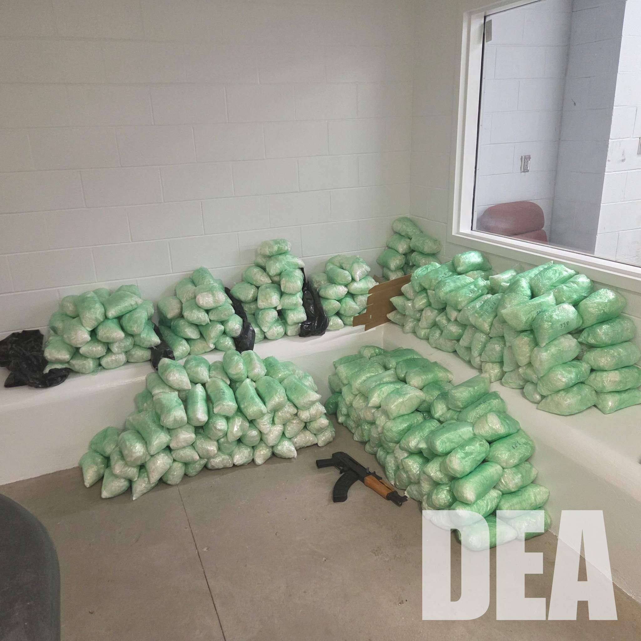 Numerous packages of what appears to be green, crystalline substance, possibly a controlled substance, scattered on the floor.