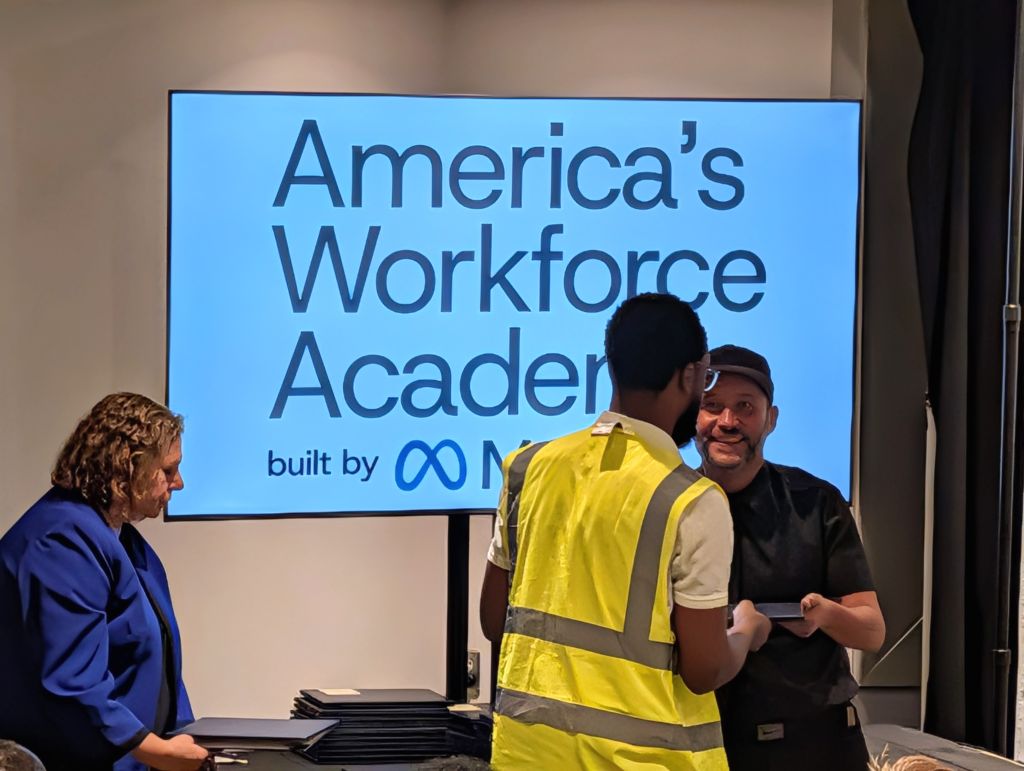 America's Workforce Academy built by Modis logo displayed on a large screen, with two people standing in front of it.