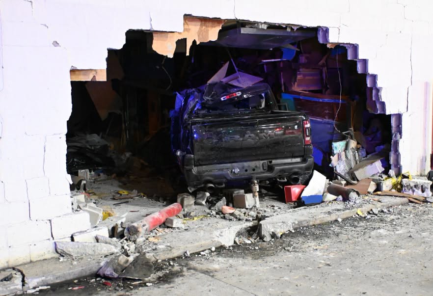 Damaged black pickup truck surrounded by debris and rubble in a dark, destroyed environment.