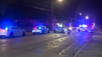Night scene of multiple police vehicles with flashing lights on a city street.