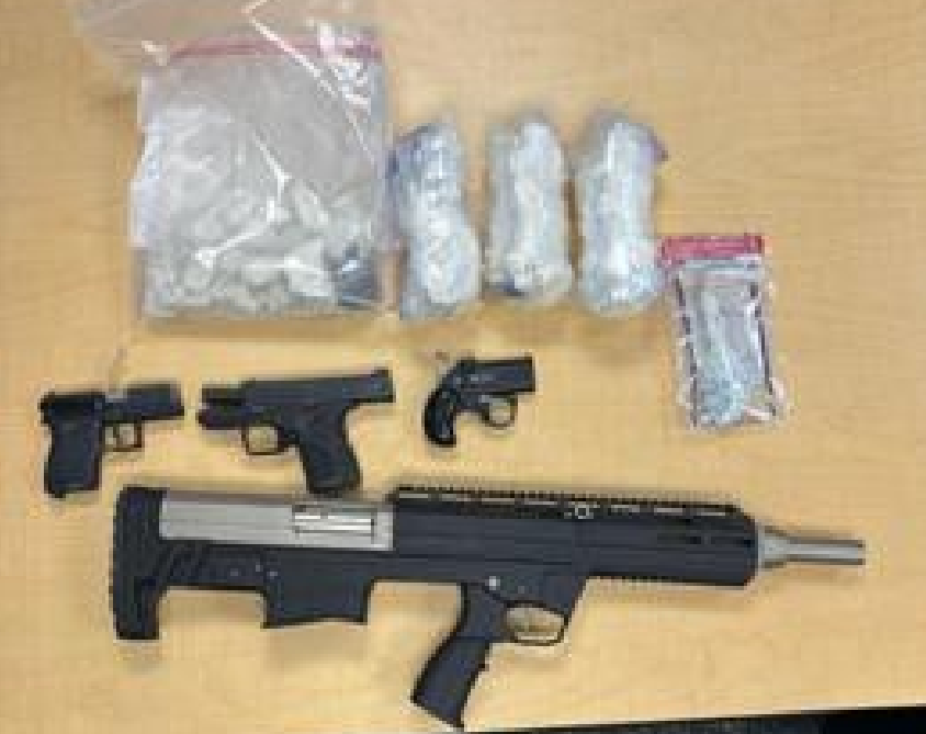 Firearms and drug paraphernalia on a wooden surface.