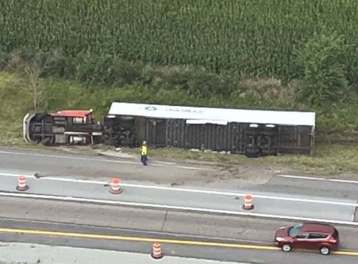 A derailed freight train on a highway, with a person visible near the overturned cars.