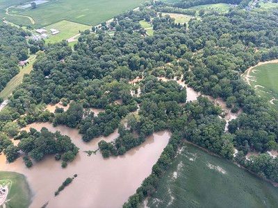 Vista aérea de una zona rural inundada con un río sinuoso y un denso bosque.