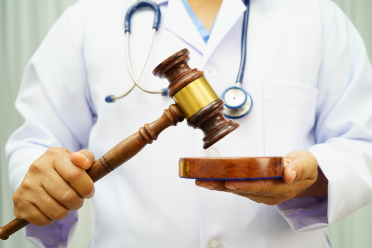 Asian doctor holding court hammer for and crime law justice, forensic medicine.