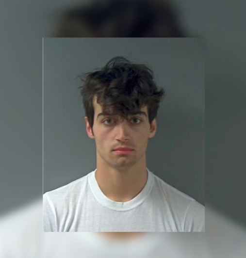 A young man with dark, messy hair looking directly at the camera with a serious expression.