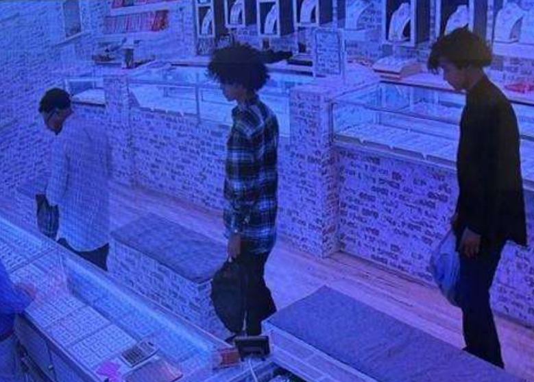Two young people standing in a dimly lit room with shelves of merchandise behind them.