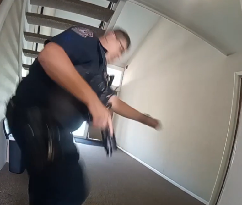 A person in a dark uniform quickly moving through a stairwell.