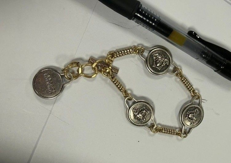 A gold-toned charm bracelet with various charms, including a Versace logo and other decorative elements.