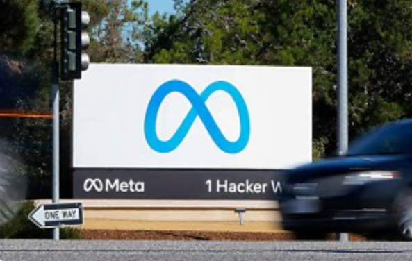 White sign with blue infinity symbol and text "Meta 1 Hacker W" on a street with a car passing by.