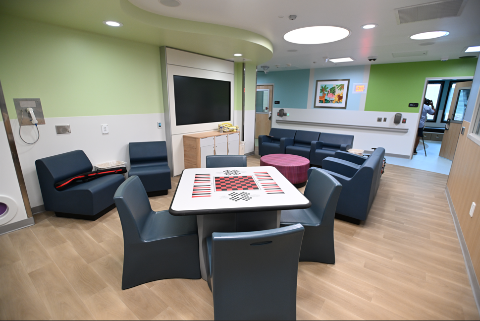A modern, colorful lounge area with a large TV, comfortable seating, and a table with a checkerboard pattern.
