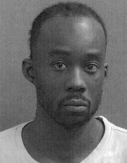 Headshot of a serious-looking Black man with a shaved head and a white shirt.